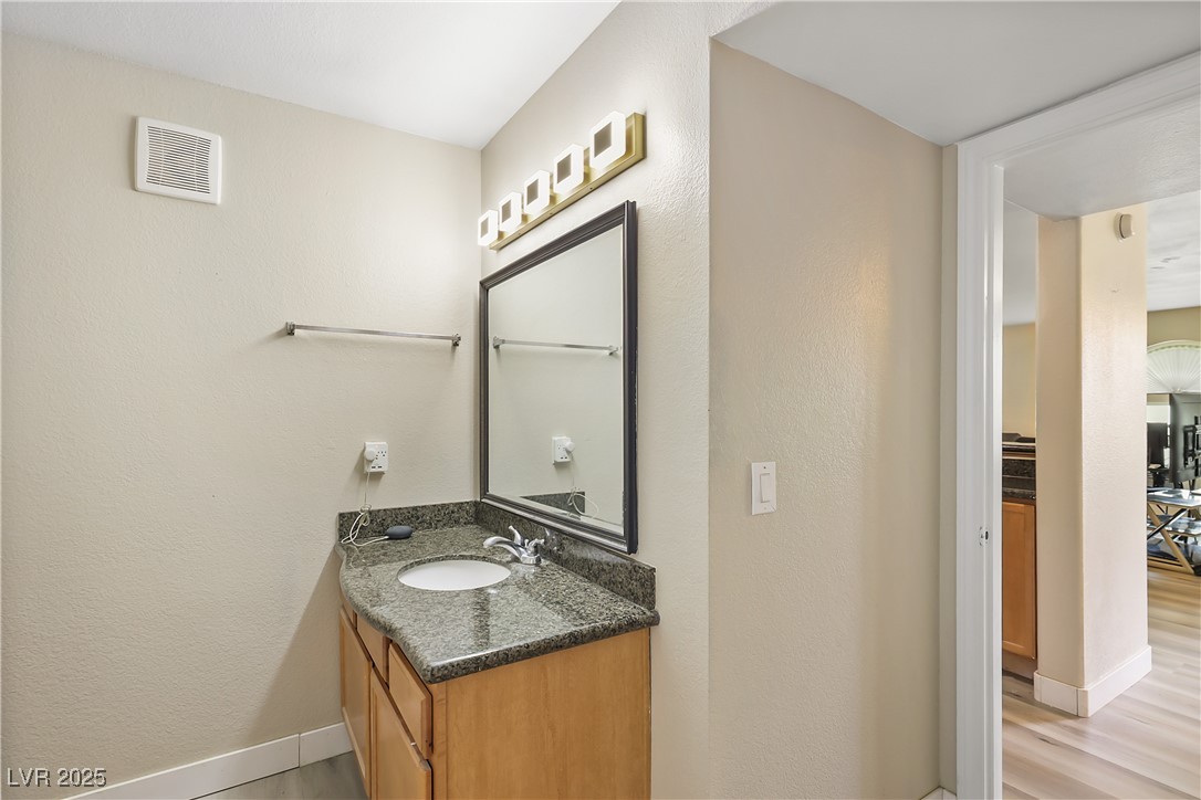 3145 East Flamingo Road, Unit 1123 Las Vegas, NV 89121 - Photo 20 of 30 Bathroom with a textured wall, vanity, and wood finished floors