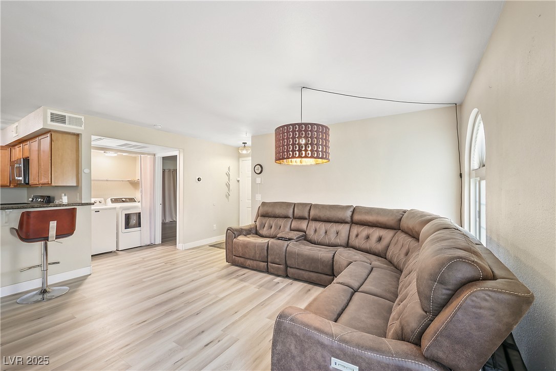 3145 East Flamingo Road, Unit 1123 Las Vegas, NV 89121 - Photo 6 of 30 Living room with washing machine and clothes dryer and light wood-style floors