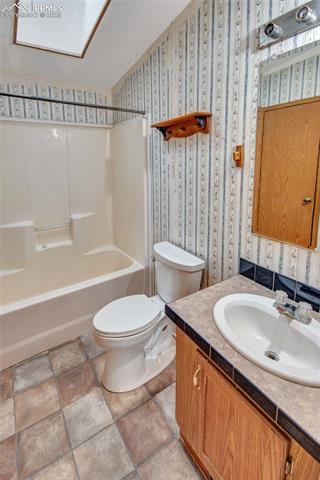 7940 Edison Road Yoder, CO 80864 - Photo 21 of 38 Bathroom featuring vanity, bathing tub / shower combination, and wallpapered walls