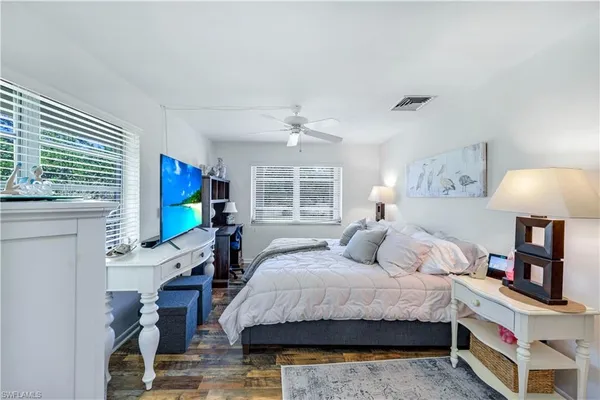 a bedroom with a bed a flat screen tv and a window