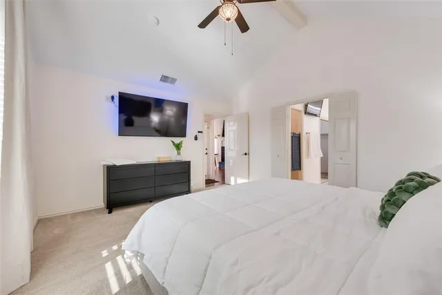 a bedroom with a bed a flat screen tv and a chandelier