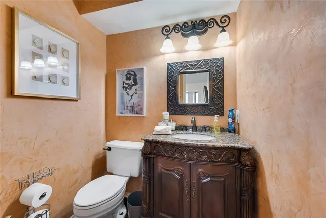 a bathroom with a granite countertop toilet sink and mirror
