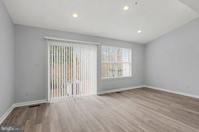 a view of empty room with wooden floor and a window