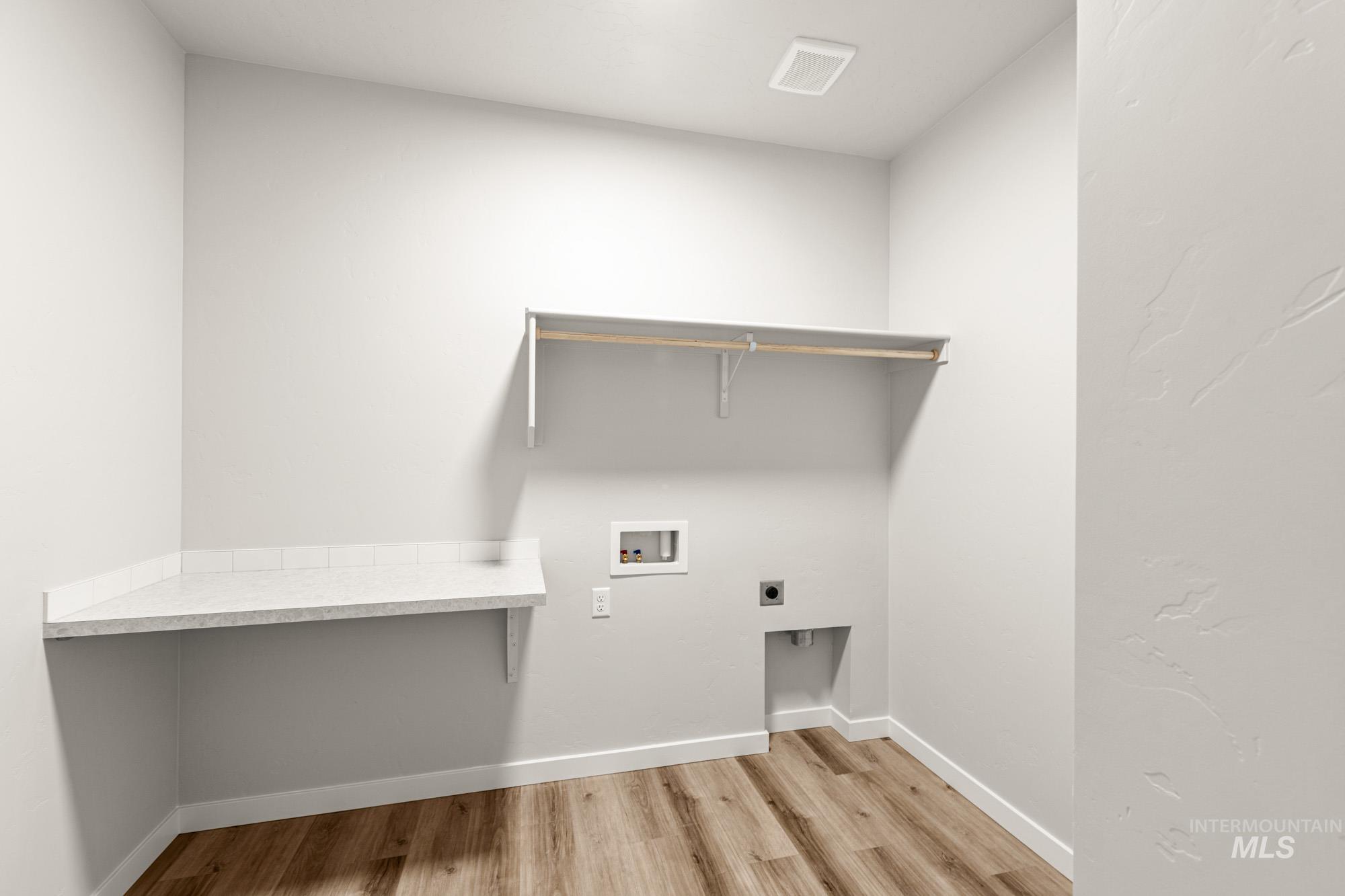 12865 Decatur Street Nampa, ID 83651 - Photo 15 of 20 Laundry area featuring wood-finish flooring, a built-in shelf with hanging rod, and a white countertop with tile backsplash