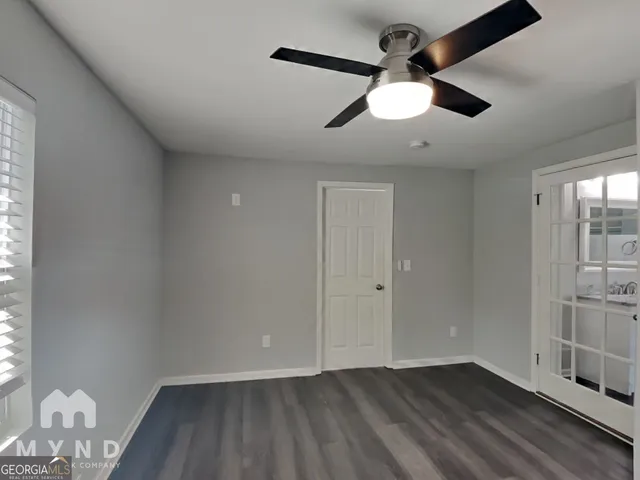 an empty room with wooden floor fan and windows
