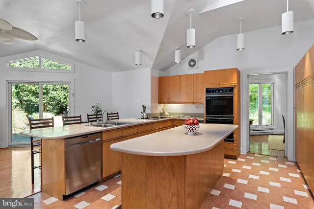 a kitchen with a sink a counter top space and living room view