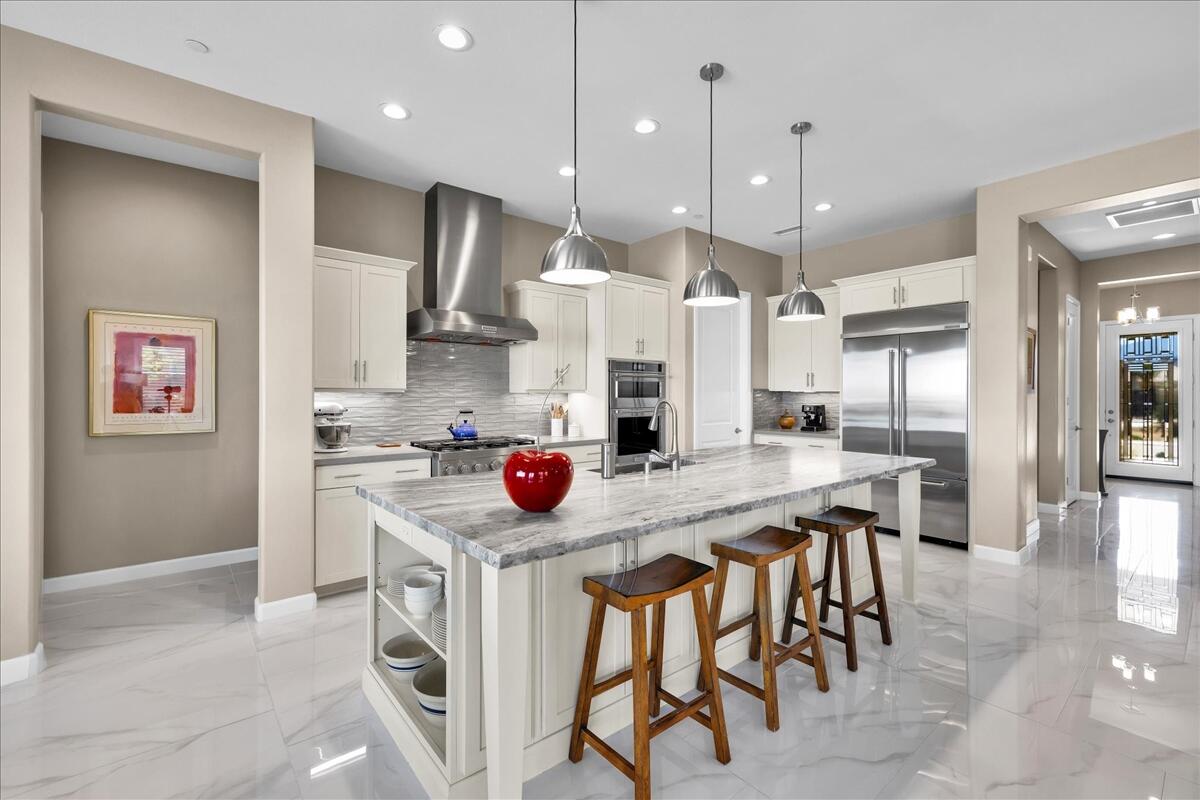 97 Zinfandel Rancho Mirage, CA 92270 - Photo 16 of 50 a kitchen with stainless steel appliances granite countertop a sink a stove a refrigerator and island with wooden floor