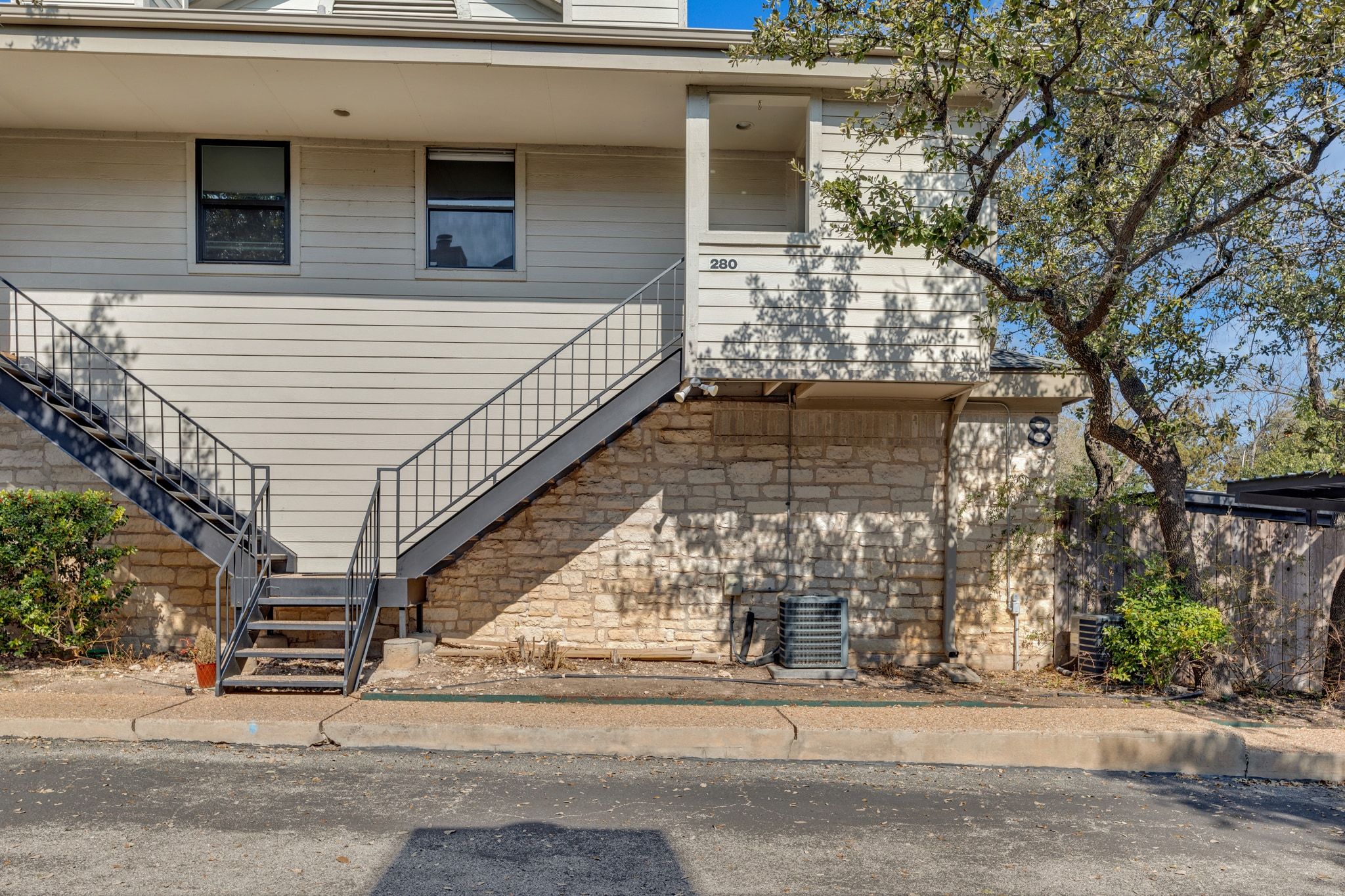 9226 Jollyville Road, Unit 280 Austin, TX 78759 - Photo 4 of 26 Exterior view of the community with classic Texas limestone accents and elevated entry, surrounded by mature trees and shaded walkways that capture the relaxed North Austin atmosphere.