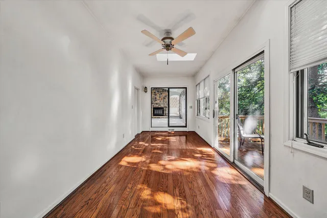 a view of a hallway with wooden floor and a ceiling fan