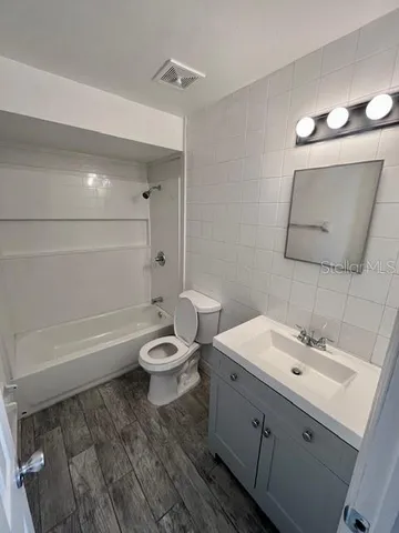 a bathroom with a toilet a sink a mirror and bathtub