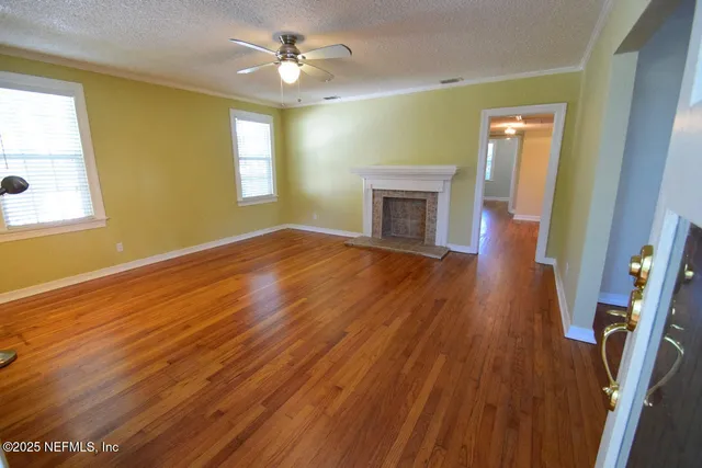 a view of empty room with wooden floor and fan