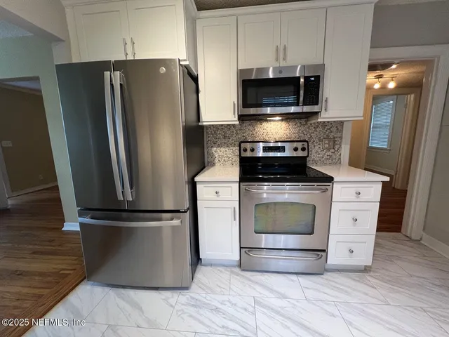a kitchen with granite countertop a refrigerator and a stove top oven