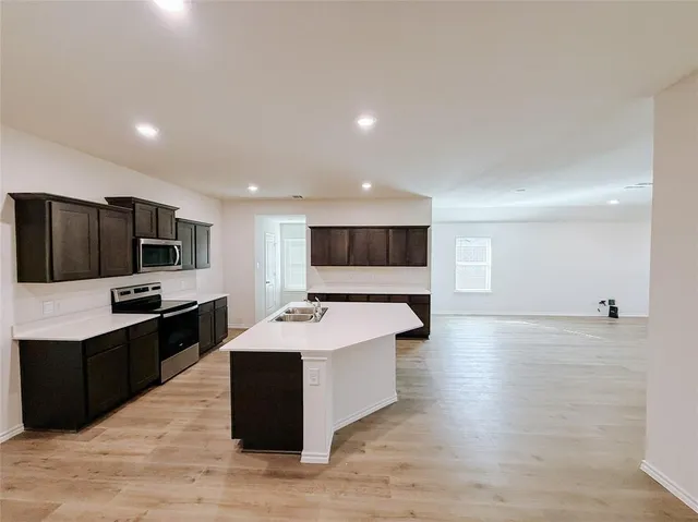 a large white kitchen with a large counter top and stainless steel appliances
