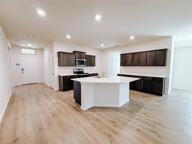 a large kitchen with a center island stainless steel appliances and cabinets