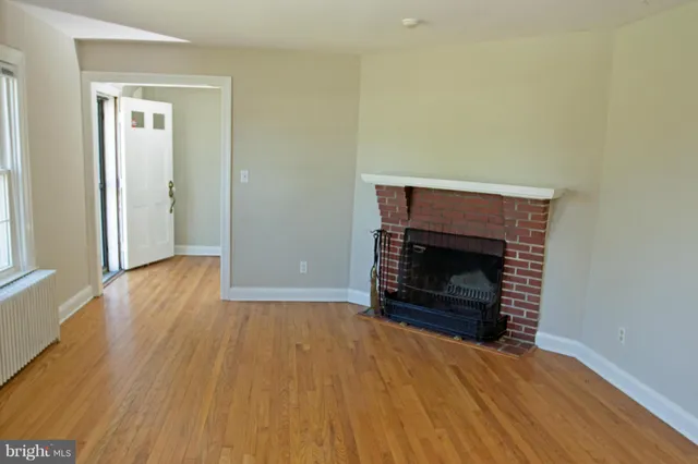 an empty room with wooden floor and fireplace
