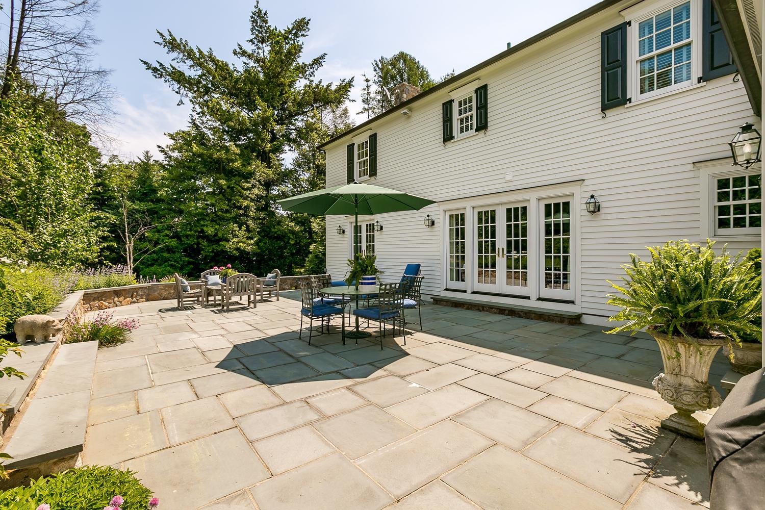 94 Marshall Ridge Road New Canaan, CT 06840 - Photo 44 of 50 a view of a patio with table and chairs under an umbrella