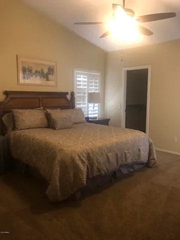 a large bed sitting in a bedroom next to a window and a chandelier