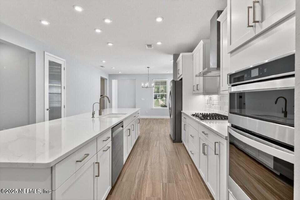 97 Kellet Way St. Johns, FL 32259 - Photo 11 of 23 a large white kitchen with granite countertop a large stove a sink dishwasher and white cabinets with wooden floor