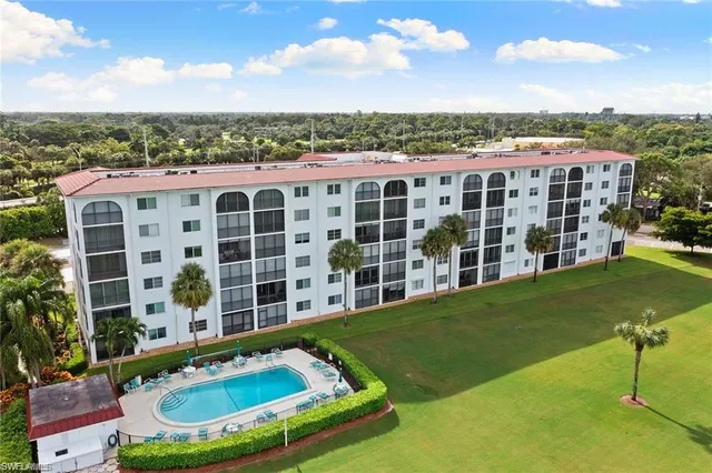 a view of a large pool with lawn chairs and a yard