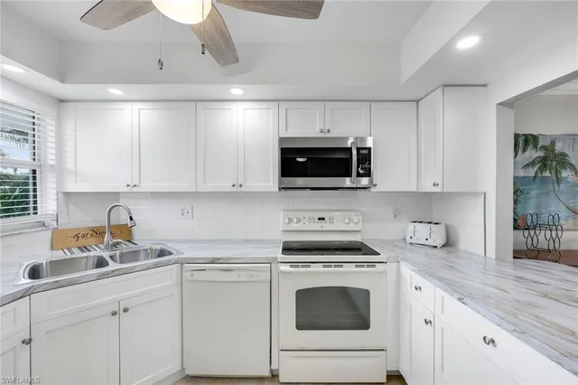 a kitchen with white cabinets and white appliances