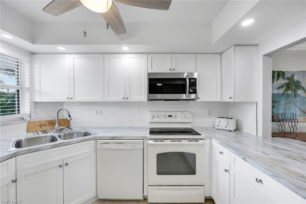37 High Point Circle East, Unit 109 Naples, FL 34103 - Photo 4 of 37 a kitchen with white cabinets and white appliances