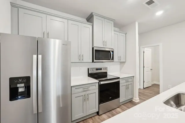 a kitchen with stainless steel appliances a refrigerator stove and white cabinets