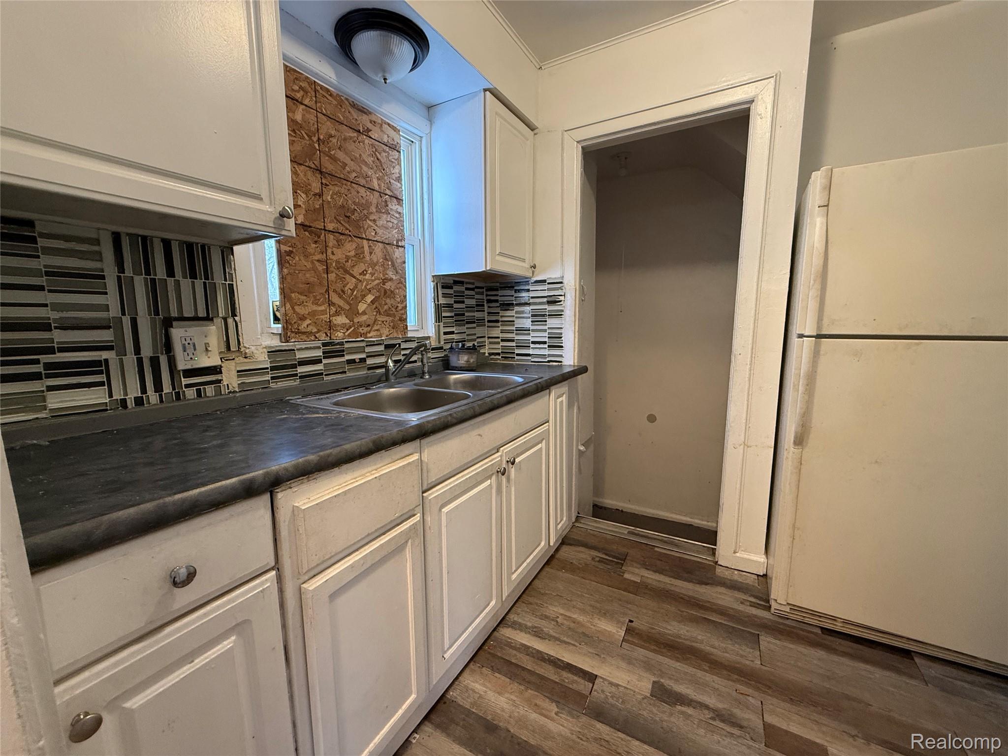 8864 Heyden Detroit, MI 48228 - Photo 12 of 16 Kitchen with freestanding refrigerator, dark countertops, dark wood-style flooring, white cabinetry, and backsplash