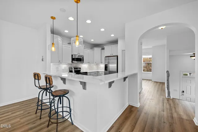 a kitchen with stainless steel appliances kitchen island granite countertop a table chairs in it and wooden floors