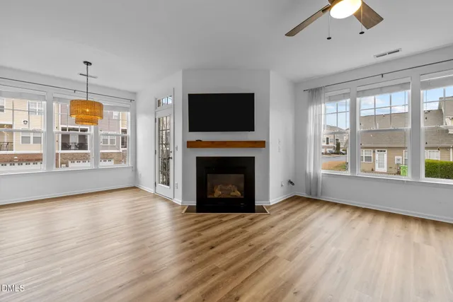 an empty room with windows fireplace and wooden floor