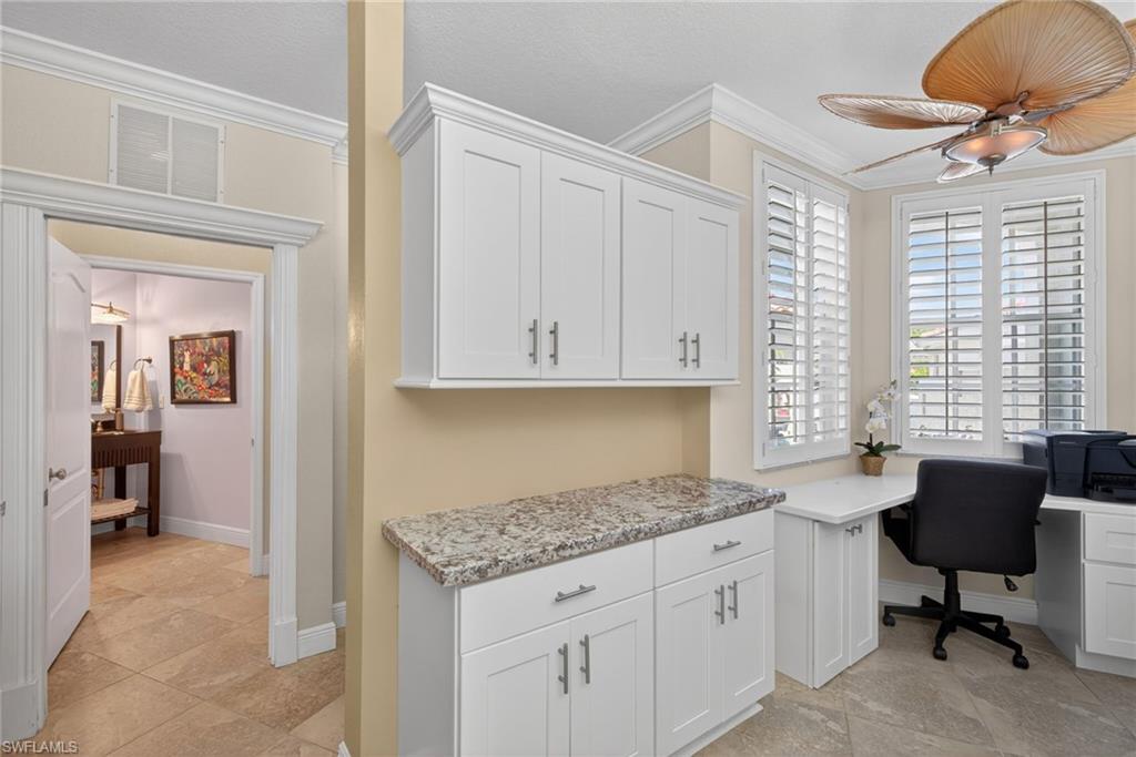 8420 Excalibur Circle, Unit R7 Naples, FL 34108 - Photo 11 of 24 This versatile space features built-in white cabinetry with a granite countertop, a dedicated desk area with ample natural light from windows with plantation shutters, and a ceiling fan