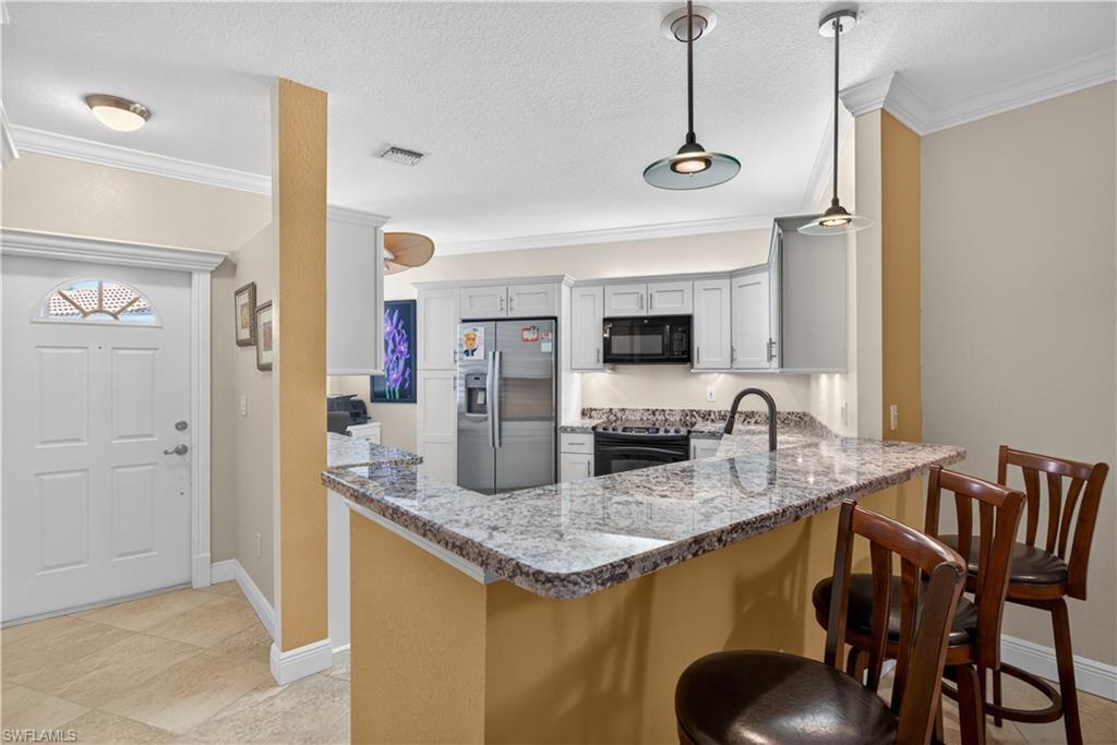 8420 Excalibur Circle, Unit R7 Naples, FL 34108 - Photo 13 of 24 The kitchen features light-colored cabinetry, a stainless steel refrigerator, and a black range and microwave