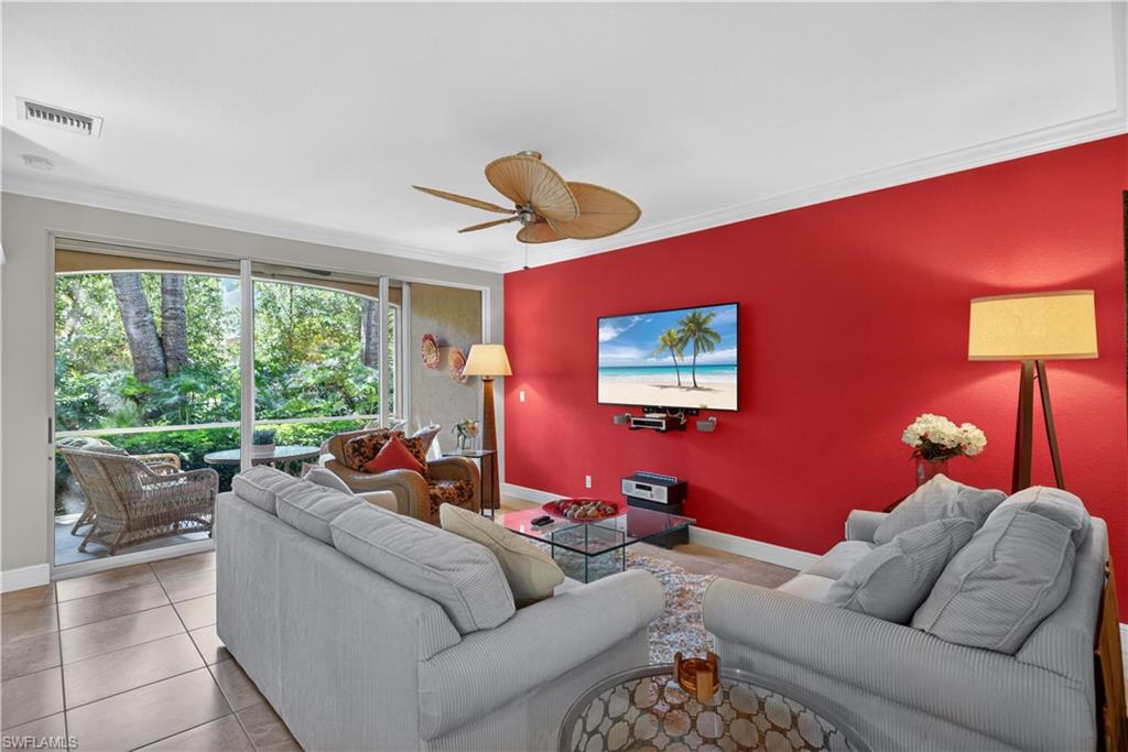 8420 Excalibur Circle, Unit R7 Naples, FL 34108 - Photo 8 of 24 Living area featuring tile flooring, a vibrant accent wall, and a ceiling fan