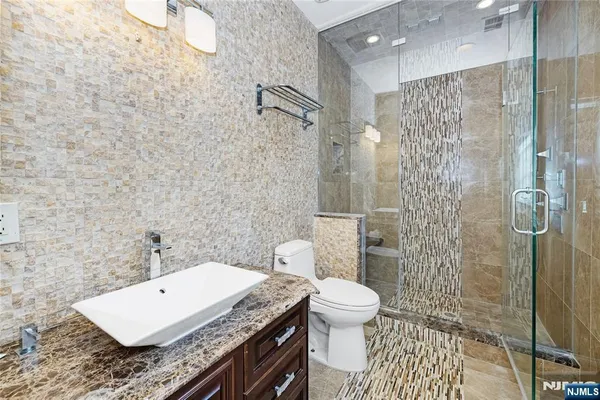 a bathroom with a granite countertop sink a toilet and shower