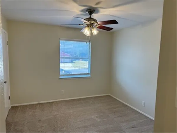 an empty room with a window and a fan