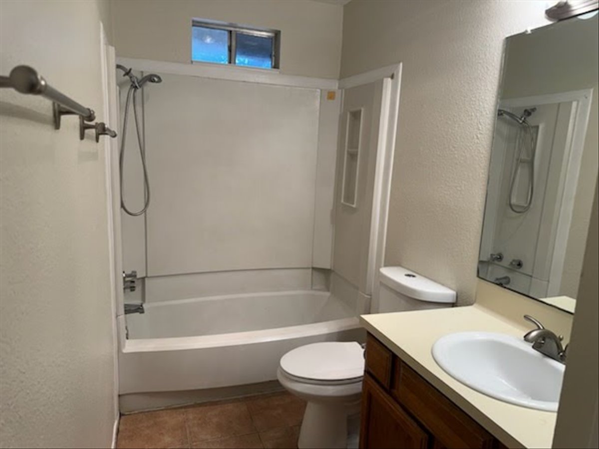 1504 Waterloo Trail, Unit A Austin, TX 78704 - Photo 10 of 12 Full bathroom with washtub / shower combination, a textured wall, vanity, and dark tile patterned flooring