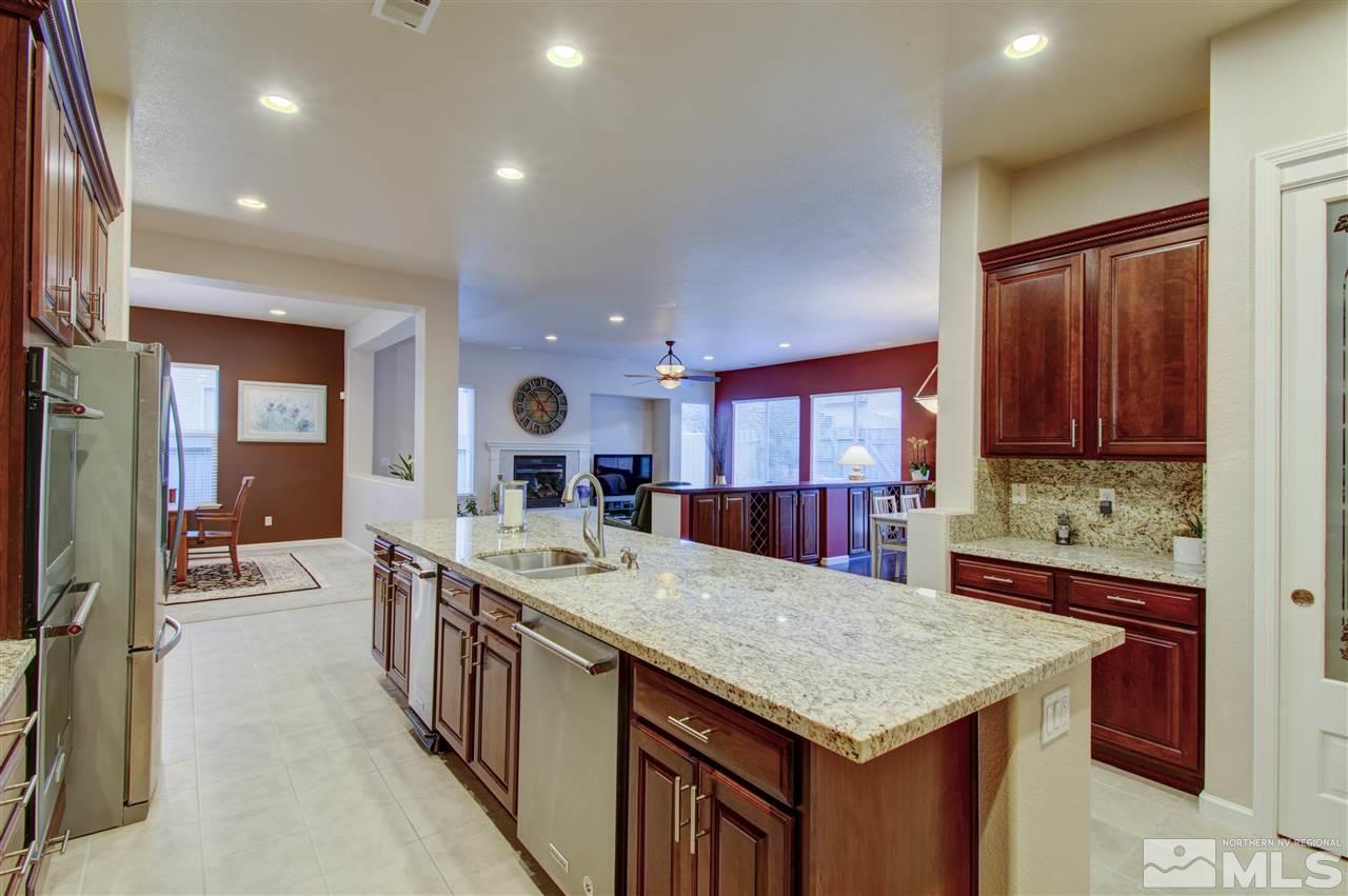 1652 Broadstone Way Reno, NV 89521 - Photo 16 of 25 a kitchen with stainless steel appliances granite countertop a kitchen island a stove a refrigerator and a sink with wooden cabinets
