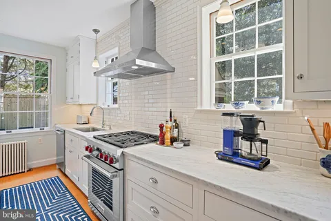 a kitchen with stainless steel appliances granite countertop a sink a stove and a wooden floor