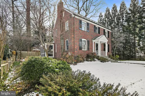 a front view of a house with a yard covered with snow and trees
