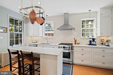 a kitchen with stainless steel appliances granite countertop a stove a sink dishwasher a dining table and chairs with wooden floor