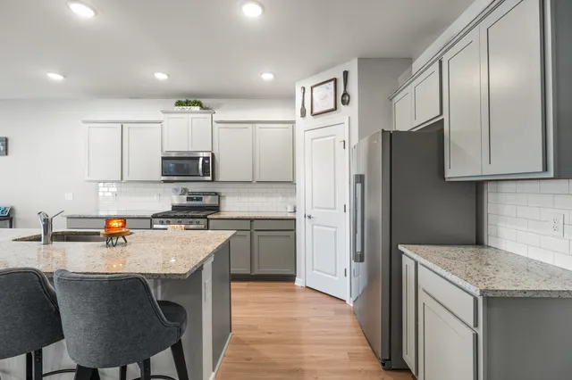 a kitchen with stainless steel appliances granite countertop a refrigerator a stove a sink a dining table and chairs