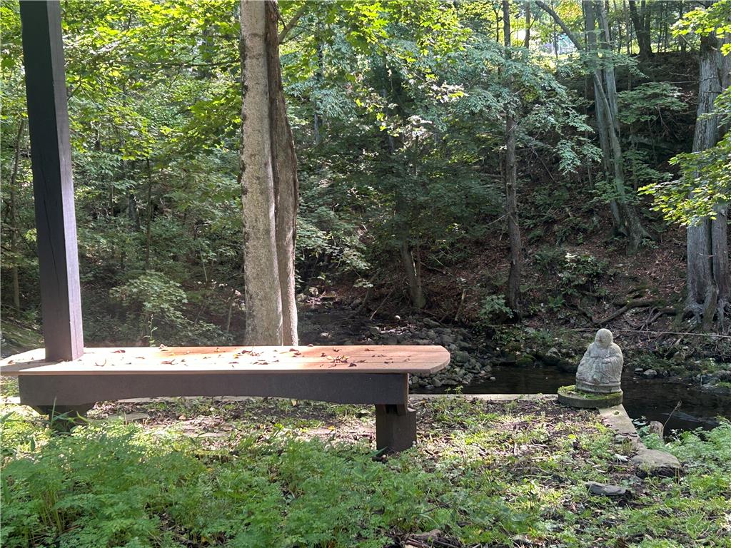 7 Allegheny Road Mount Bethel, PA 18343 - Photo 22 of 71 A quiet wooden bench overlooks a gentle flowing stream surrounded by mature forest trees.
