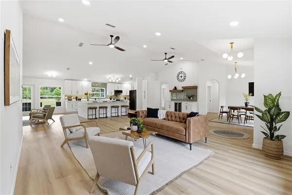 a living room with furniture kitchen view and a wooden floor