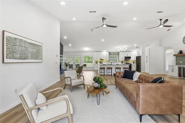 a living room with furniture kitchen view and a chandelier
