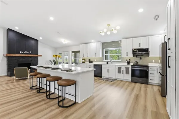 a kitchen with stainless steel appliances a stove a sink a kitchen island with chairs and wooden floor