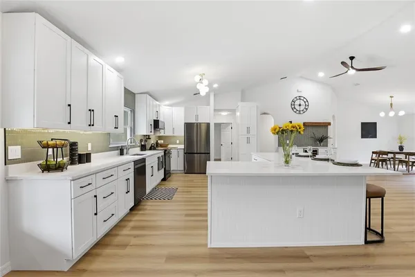 a large kitchen with kitchen island a stove a sink a center island and cabinets