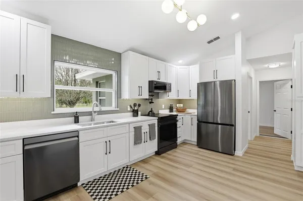 a kitchen with a sink cabinets stainless steel appliances and a window