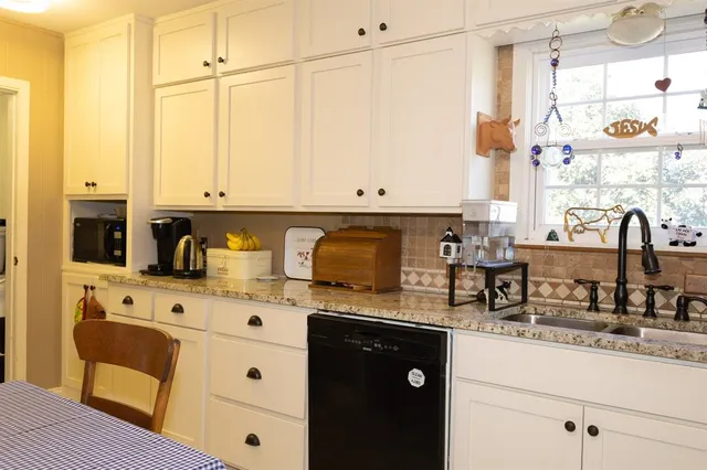 a kitchen with stainless steel appliances granite countertop a stove a sink and white cabinets