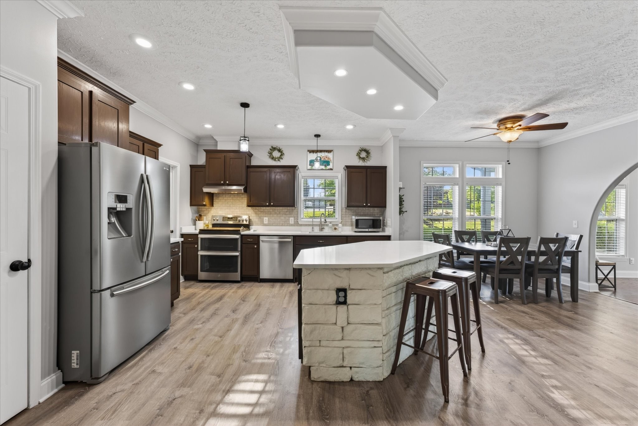 2108 Buckskin Court Spring Hill, TN 37174 - Photo 14 of 39 a kitchen with stainless steel appliances kitchen island granite countertop a refrigerator a stove a sink a dining table and chairs with wooden floor