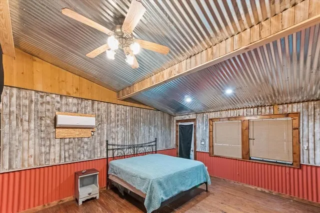 a bedroom with a bed and a large window with wooden floor