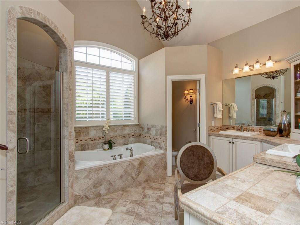 8404 Oakchester Court Oak Ridge, NC 27310 - Photo 10 of 30 Master bathroom with jetted tub, multiple head shower with built in seat, chandelier and vaulted ceiling.